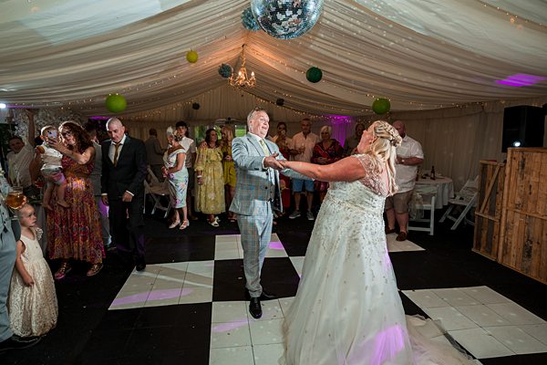 Couple dancing at wedding reception with guests watching.