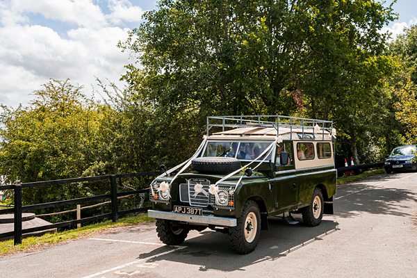 Vintage green Land Rover on sunny country road.