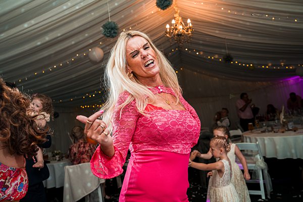 Woman dancing joyfully at festive event under tent.