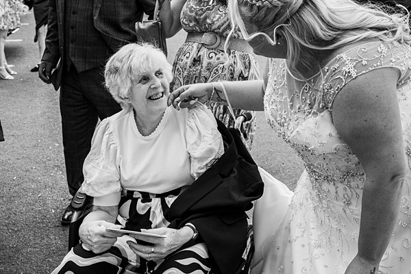 Wedding interaction: bride with elderly woman in wheelchair.