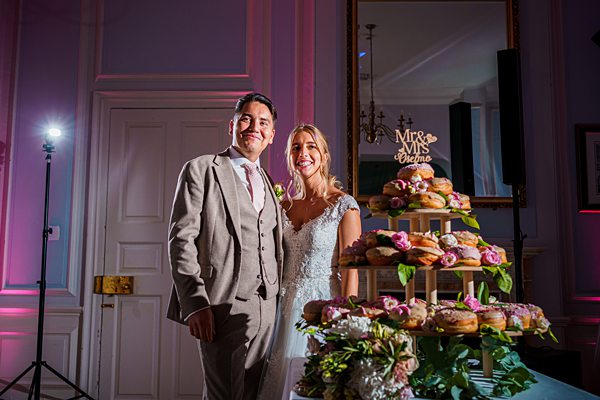 Bride and groom smiling by wedding cake display.