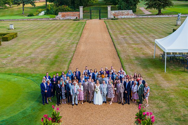 Outdoor wedding group photo on manor estate lawn.