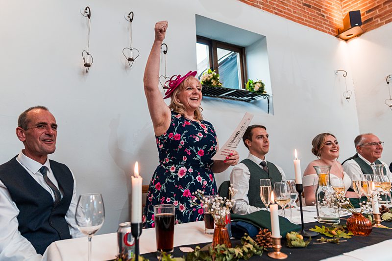 Woman cheering at festive dinner table celebration.