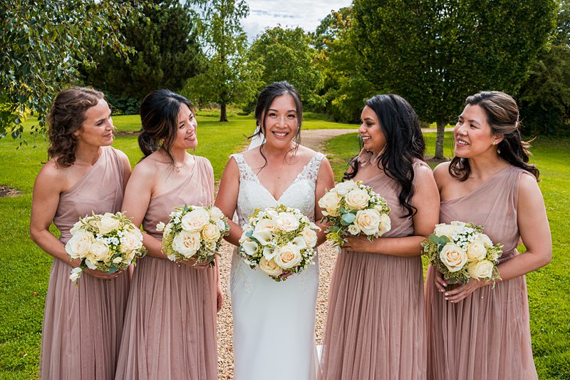 Bride and bridesmaids with bouquets, outdoor wedding.