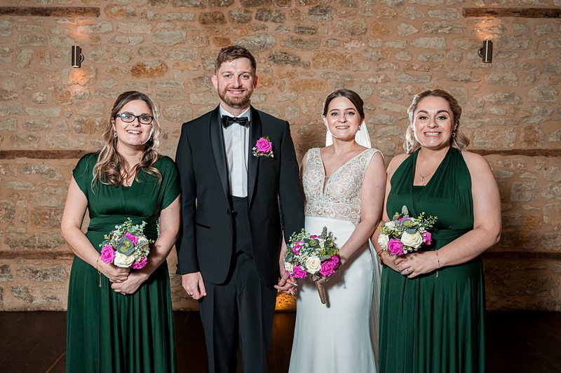 Bride, groom, and bridesmaids with bouquets at wedding.