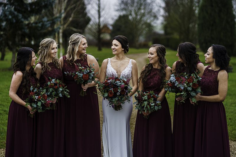 Bride with bridesmaids holding bouquets outdoors.