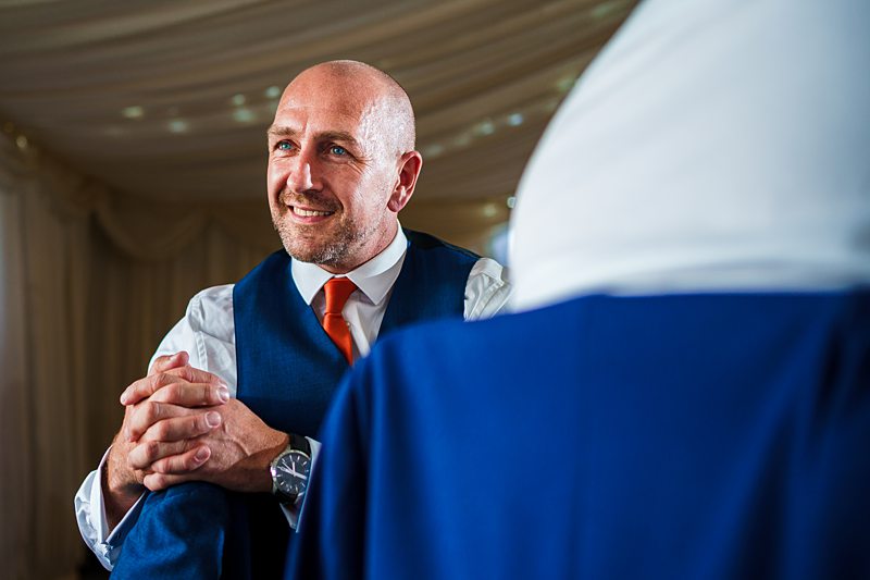 Man in waistcoat smiling at a wedding.