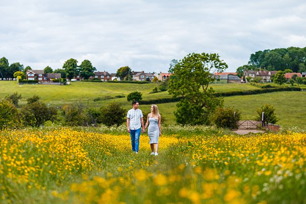 Couple walking in blooming meadow, UK countryside.