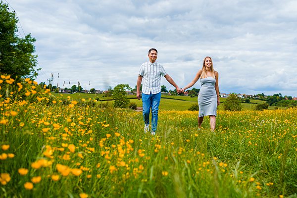 Couple walking in blooming meadow, holding hands.