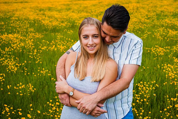 Couple embracing in blooming yellow flower field.