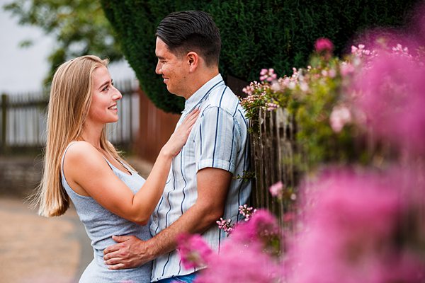 Couple embracing near flowers in a garden.