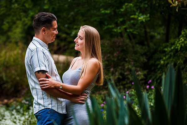 Couple embracing in a lush garden setting.