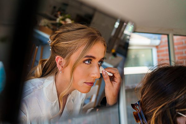 Woman applying makeup in mirror.