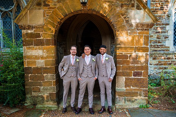 Three men in suits at church entrance.