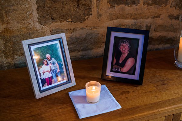 Framed photos and candle on wooden table.