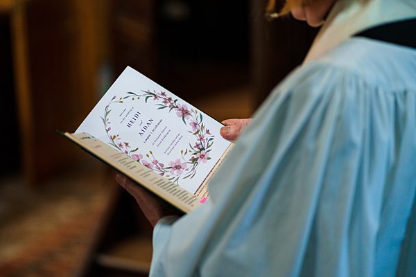 Person reading floral wedding program booklet.