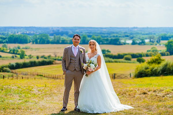Bride and groom smiling in sunny countryside wedding.