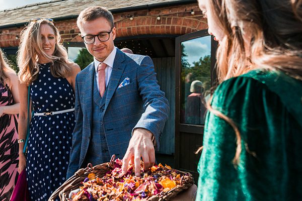 Man picks petals from basket at outdoor event.