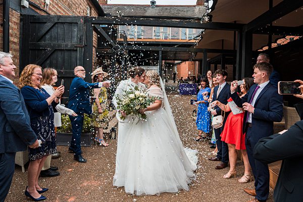 Bride and groom celebrate with confetti toss.