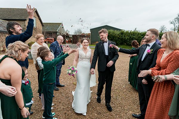 Joyful wedding couple with confetti and guests.