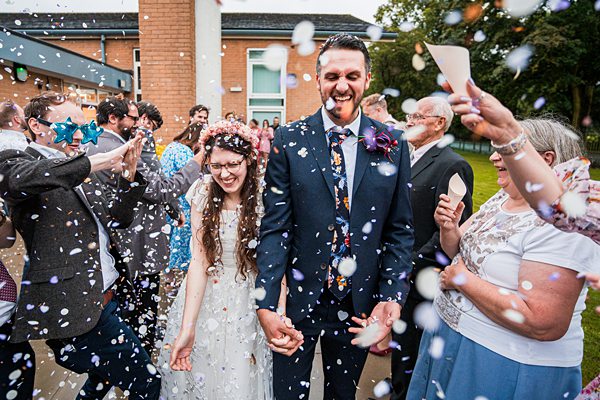 Bride and groom enjoying confetti shower at wedding.