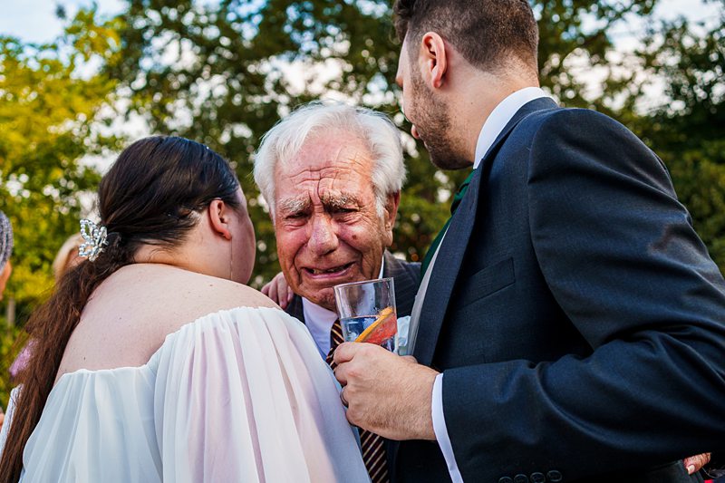 Elderly man emotional at wedding with couple