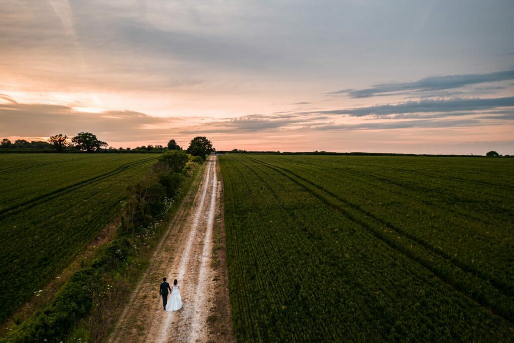 Wedding couple walking in field at sunset