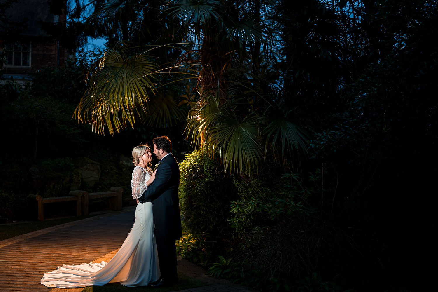 Couple kissing at night, tropical garden setting.