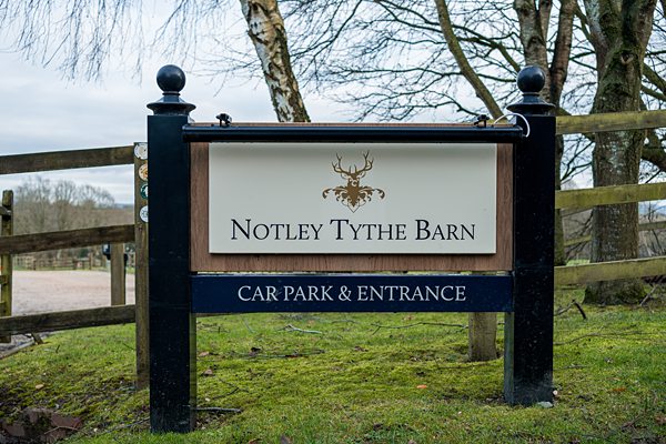 Notley Tythe Barn sign with logo, parking directions.