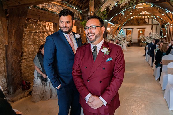 Two men smiling at wedding venue with fairy lights.