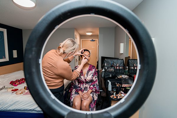 Makeup artist applying makeup to woman, ring light view.