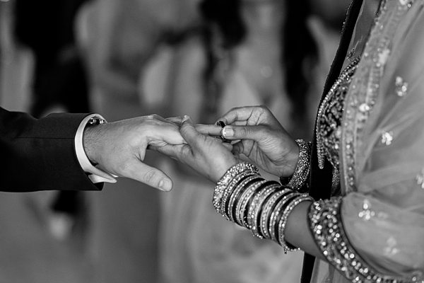 Exchanging rings at wedding ceremony in black and white.