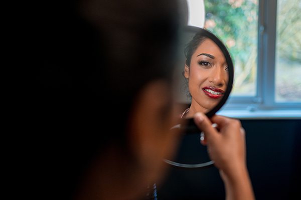 Woman applying lipstick in mirror reflection.
