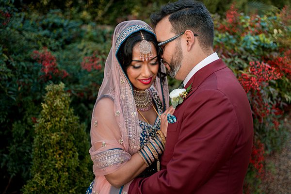 Couple in traditional Indian wedding attire embracing outdoors