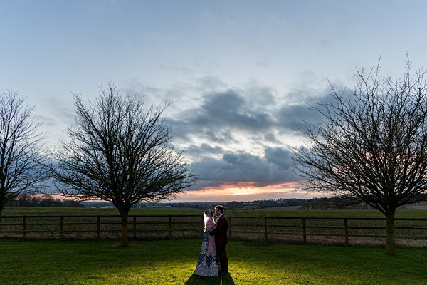 Couple embracing at sunset in countryside.