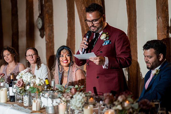 Man giving speech at wedding reception table.