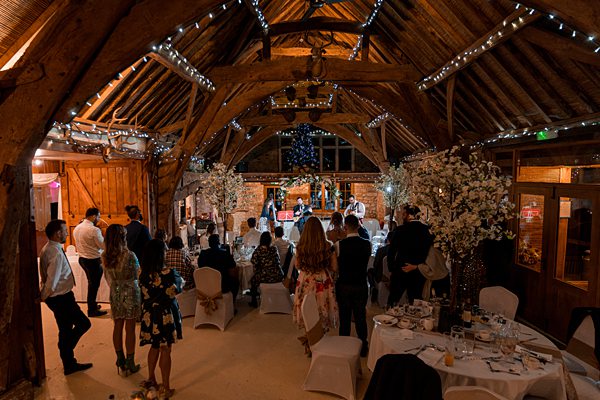 Rustic barn wedding ceremony with guests and fairy lights.