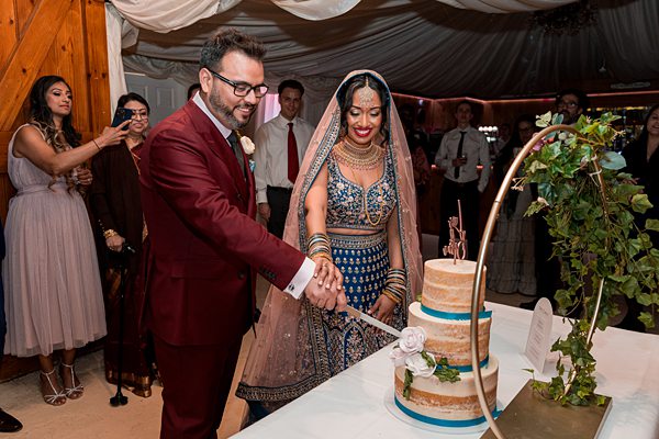 Couple cutting cake at multicultural wedding ceremony.