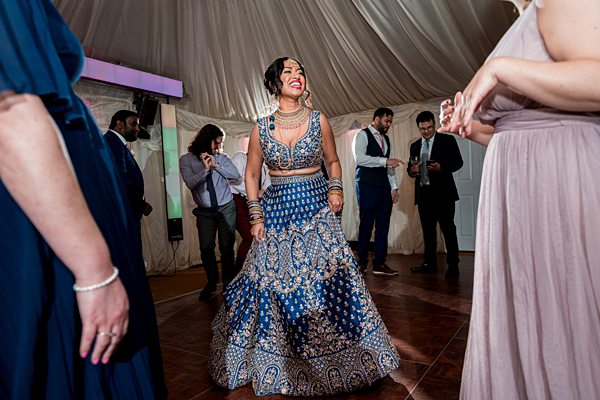 Woman dancing in blue traditional outfit at wedding reception.