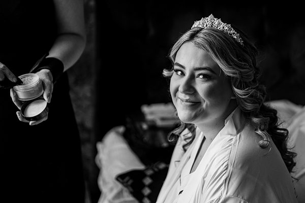 Bride smiling, makeup application, black and white photo.