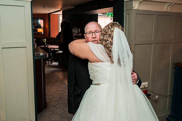 Bride hugging man at wedding reception.