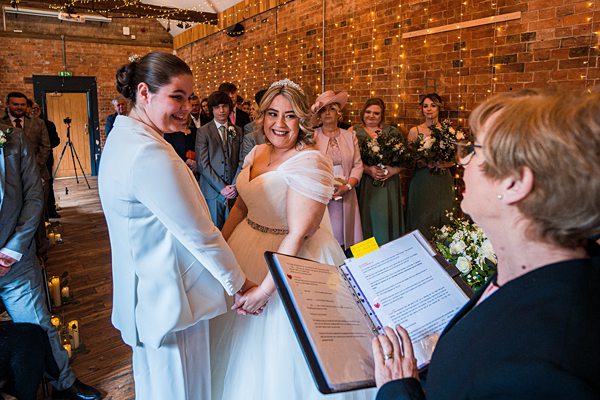 Same-sex wedding ceremony with brides and guests.
