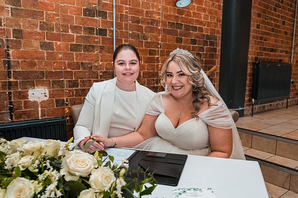 Bride and companion at wedding table with flowers.