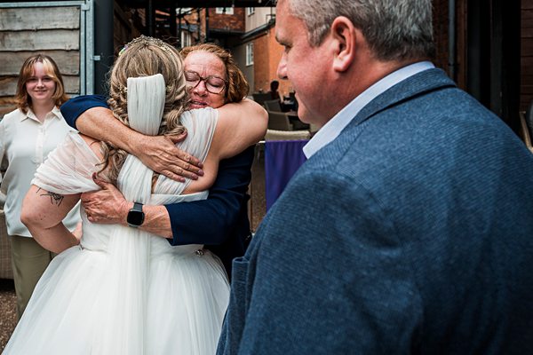 Emotional wedding hug with joyful guests.