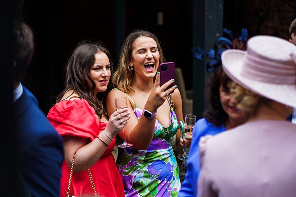 Women laughing at event with smartphone.