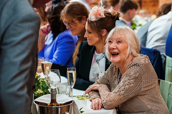 Elderly lady laughing at festive event with guests.