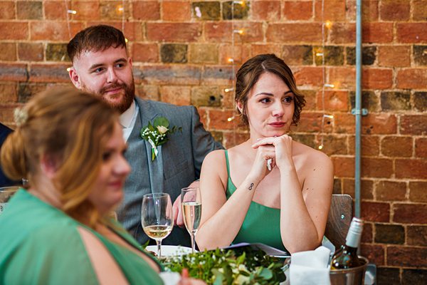 Guests at wedding reception with brick wall background.