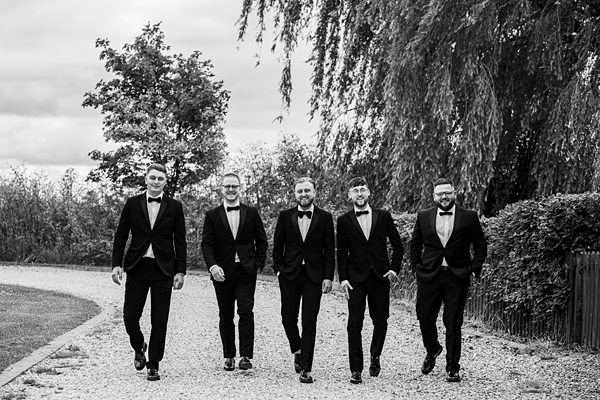 Five men in tuxedos walking outdoors