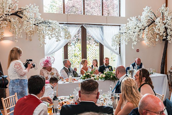 Wedding reception with guests and bride and groom at table.