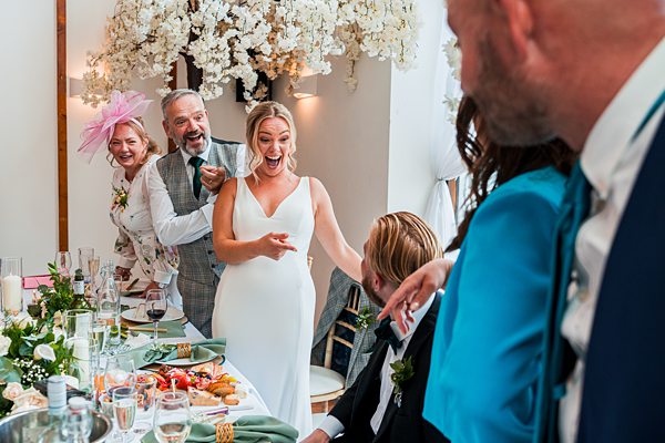 Joyful wedding reception with laughing bride and guests.